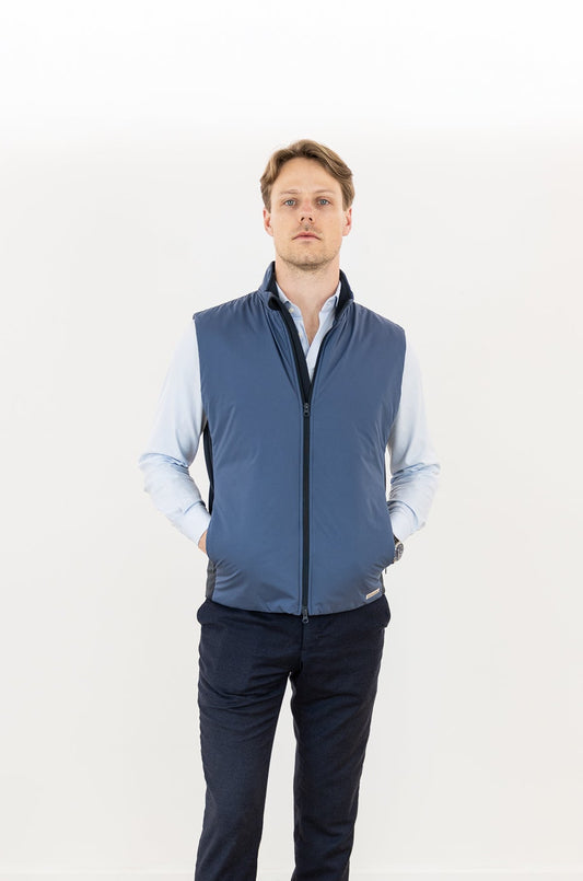 Man wearing a blue vest over a light blue shirt on a white background